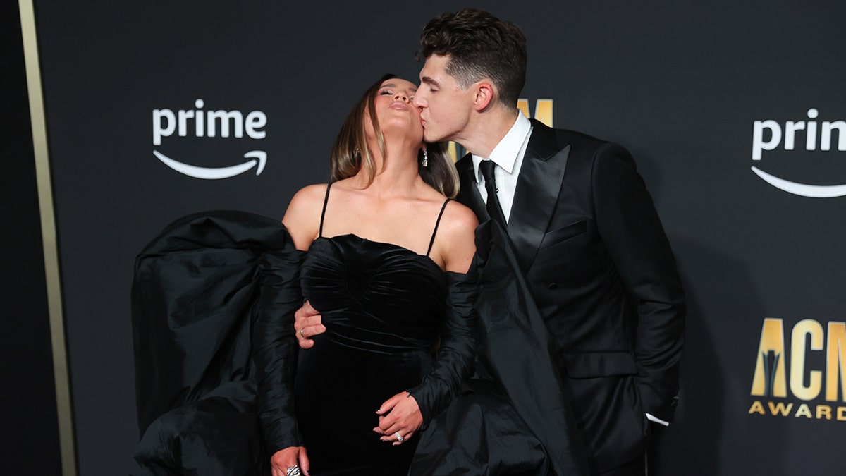 Gabby Barrett gets a kiss form husband Cade Foehner on the carpet at the Academy of Country Music Awards