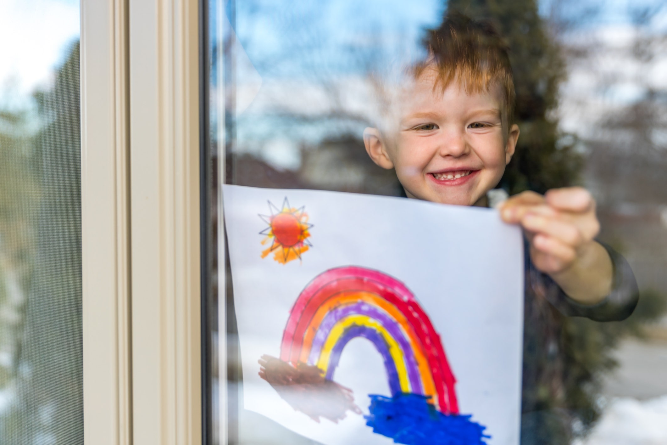 Young Boy sticking his drawing on home window