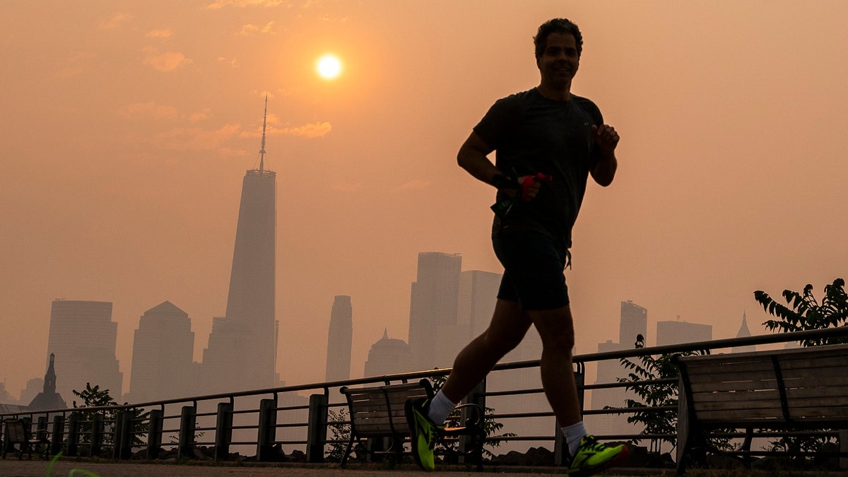 A man jogs through the Liberty State Park while the smoke from Canada wildfires covers the Manhattan borough